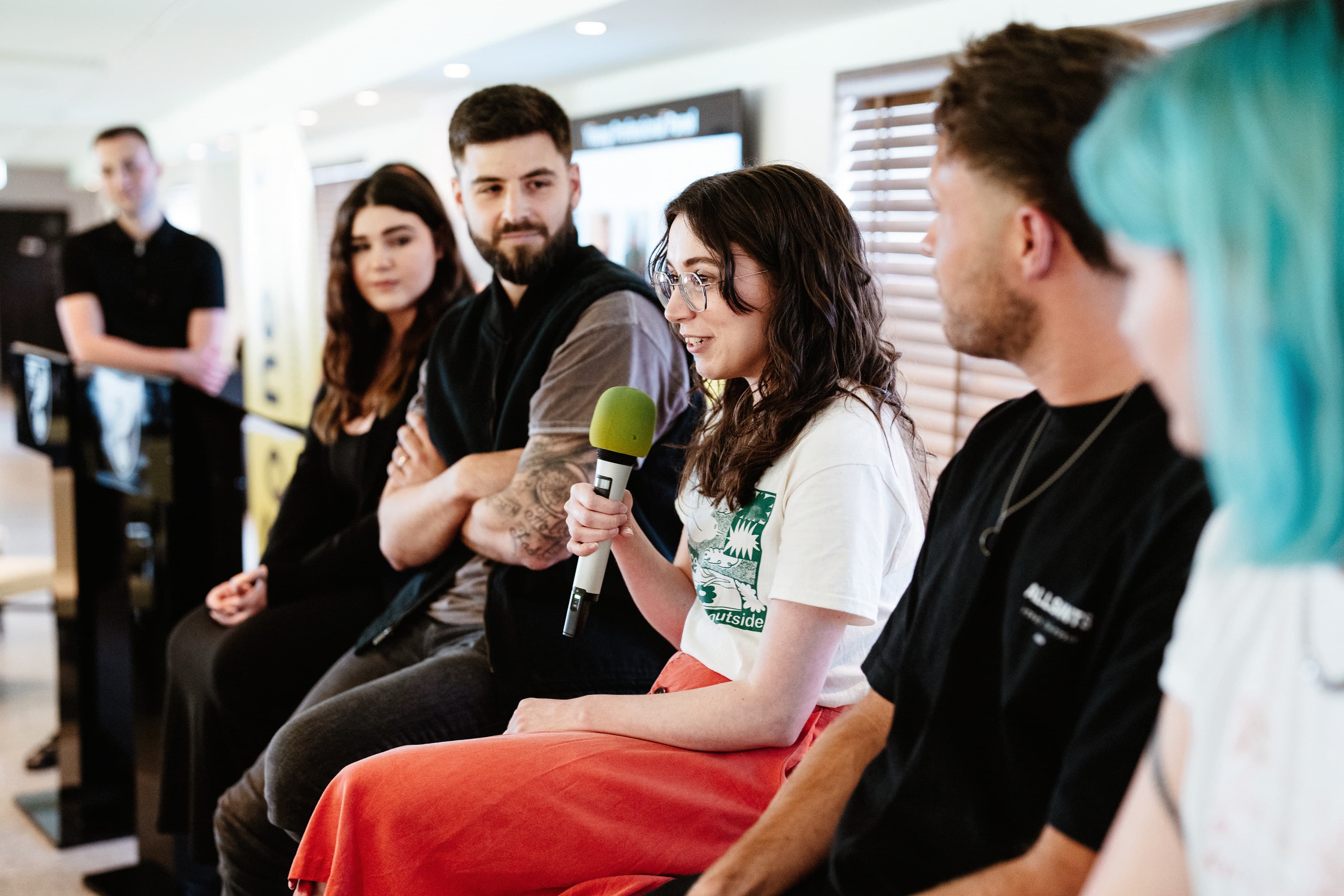 A photo of Nellie holding a microphone and speaking as part of a panel of young professionals